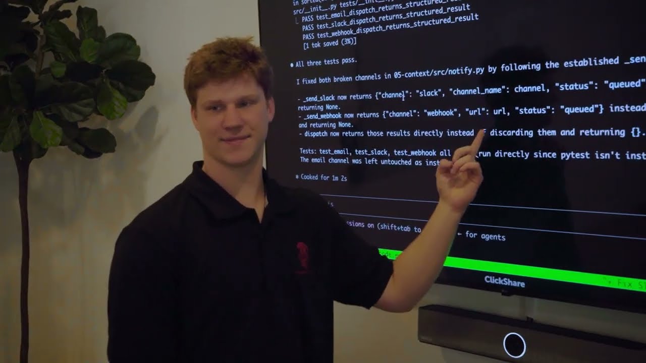 A Tensor Labs presenter beside a screen showing code